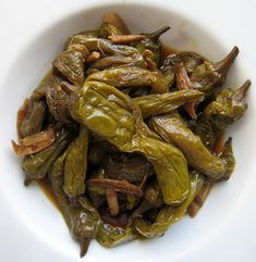 a white bowl filled with cooked green peppers