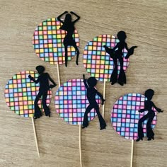 four cupcake toppers with the silhouettes of people on them, all made out of colored squares