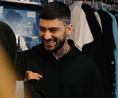 a man with tattoos on his face smiles while looking at another person's shirt