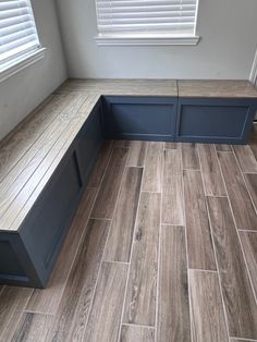 a bench sitting on top of a wooden floor next to a window