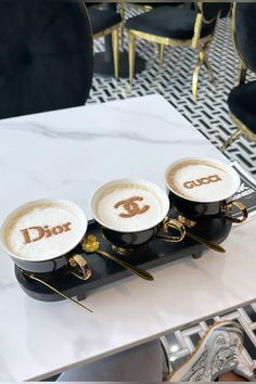 three coffee cups with the word dior on them are sitting on a marble table