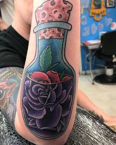 a woman with a tattoo on her leg has a rose in a glass jar filled with water