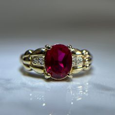 Beautiful red gemstone and diamond ring in a vintage like style and intricate gold band detailing. One large oval cut synthetic ruby centre stone, prong set. Two small pave set diamonds on each side of the centre ruby.  Pre-loved item. Stamped 14KT yellow gold.  Ring Size 9.25 US Weight: 5.110g **FREE shipping within Canada and USA** If you have any questions or concerns, please do not hesitate to contact us. We will be more than happy to help you and answer any inquiries.  We invite you to chec Classic Red Ruby Ring, Oval Cabochon, Classic Red Ruby Ring With Oval Cabochon, Classic Red Oval Diamond Ring, Red Diamond Oval Cabochon Ring, Elegant Ruby Rings With Oval Cabochon Center Stone, Ruby Rings With Center Stone, Oval Cabochon Shape, Classic Oval Lab-created Ruby Diamond Ring, Oval Ring With Lab-created Ruby And Accent Stones, Formal Ruby Ring With Oval Cabochon Center Stone