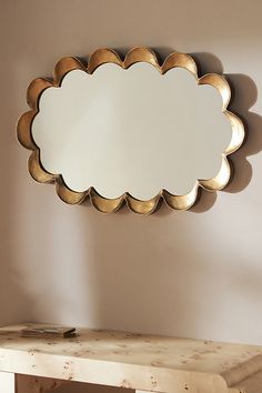 a mirror sitting on top of a wooden table in front of a wall mounted scallop