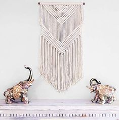 two elephants standing next to each other in front of a macrame wall hanging