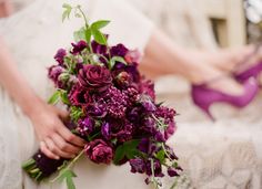 a bridal holding a bouquet of flowers and purple high heeled shoes in front of her