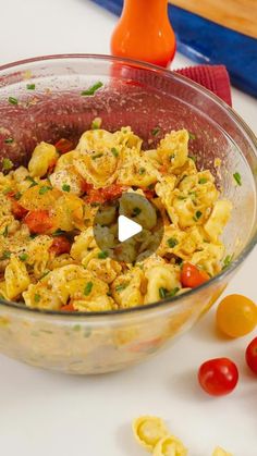 a bowl filled with food sitting on top of a table next to tomatoes and peppers