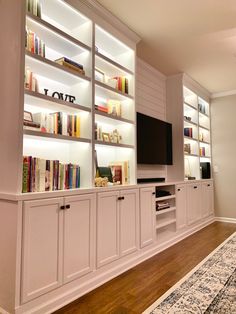 a living room filled with lots of white bookshelves next to a large rug