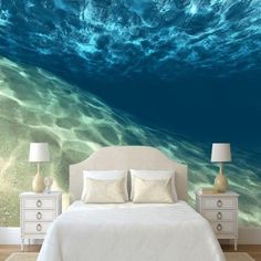 a bedroom scene with focus on the bed and ocean wallpaper that has an underwater view