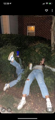 two people laying on the ground in front of a house with their arms around each other