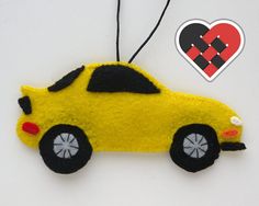 a felt car ornament hanging from a string with a heart on it's side