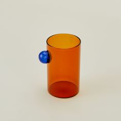 an orange glass cup with a blue ball in it