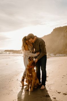 a man and woman kissing on the beach with their dog