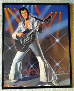 elvis presley playing guitar on stage in front of an audience with his arms outstretched and legs spread out