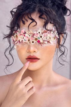 a woman with flowers on her face and nose is posing for the camera while wearing a flower crown