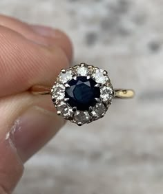 a close up of a person holding a ring with a blue and white diamond in it