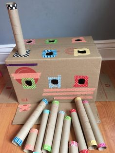 a cardboard box with several rolls of toilet paper in front of it on the floor