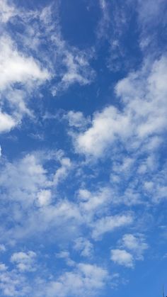 an airplane is flying high in the blue sky with white clouds and some green trees