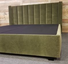 a bed with a green velvet headboard and foot board