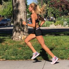 a woman running down a sidewalk next to a tree