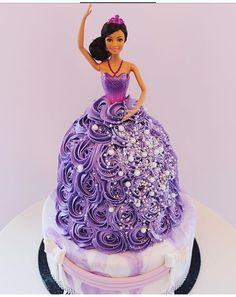 there is a cake that looks like a princess on top of the cake and has purple icing