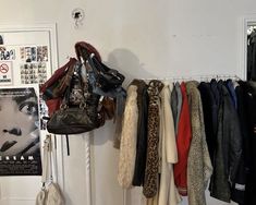 there are many coats and purses hanging on the wall