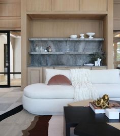 a living room filled with furniture next to a wall covered in shelves and vases