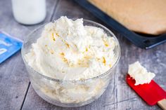 a glass bowl filled with whipped cream next to a loaf of bread