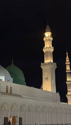 a tall white building with a clock on it's side and two towers in the background