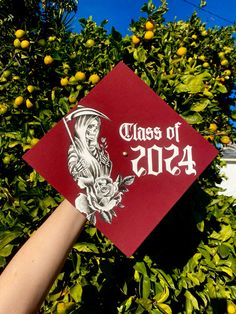 a hand holding a red graduation cap that says class of 2013 with a skeleton and roses on it