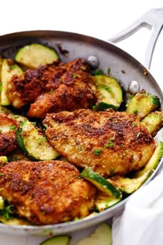 a pan filled with chicken and zucchini on top of a table