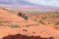 an off - road vehicle is driving on the side of a cliff in the desert