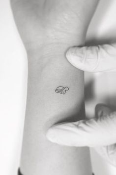 a woman's wrist with a small tattoo on the left side of her arm