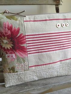 a white purse with red flowers and buttons on the front is sitting on a bench