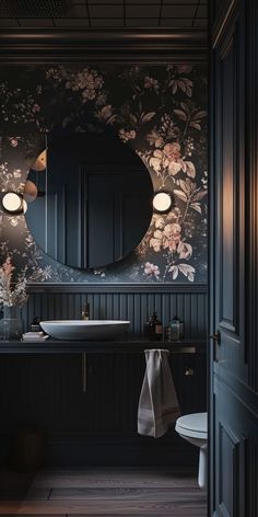 a bathroom with floral wallpaper and dark wood flooring is seen in this image