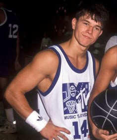 two men standing next to each other holding basketballs