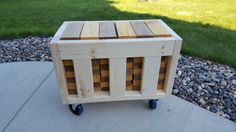 a wooden crate sitting on top of a sidewalk next to a grass covered park area