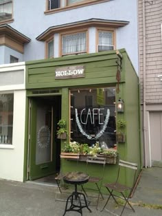 an outside cafe with tables and chairs in front of the building that is painted green