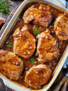 meat and gravy in a white casserole dish on a wooden table