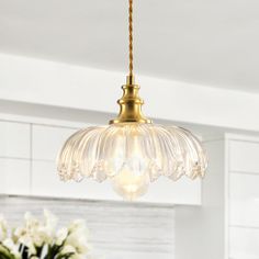 a chandelier hanging from a ceiling in a kitchen with flowers on the table