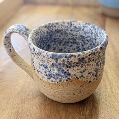 a blue and white cup sitting on top of a wooden table