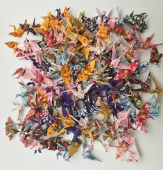 a pile of origami cranes sitting on top of a white table next to each other