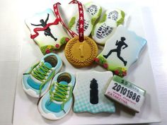 decorated cookies in the shape of tennis shoes and medals on a white plate with a red ribbon