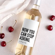 a bottle of wine sitting on top of a table next to some cherries and a napkin