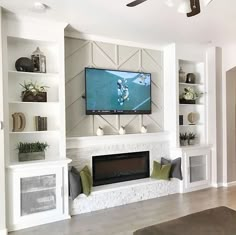 a flat screen tv mounted on the wall above a fireplace in a living room with built - in shelving