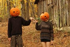 two people wearing pumpkin heads in the woods