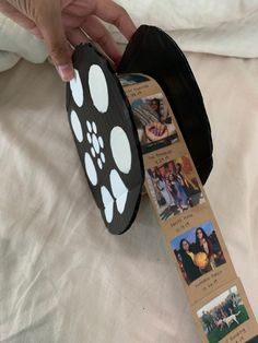 a person is holding a black ribbon with white paw prints on it and there are pictures attached to it