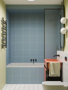 a bathroom with blue tiles and a white bathtub next to a red counter top