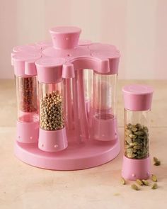 a pink spice dispenser sitting on top of a counter next to a pepper mill