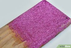 a wooden cutting board with pink glitter on it